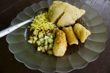 pempek kızarmış balık ve tapyoka, salatalık dilimleri, sirke sosu veya sirke sosu adı verilen tatlı ve ekşi soslu sarı erişte. Cam levhalarda servis edilen izole ahşap arka plan 