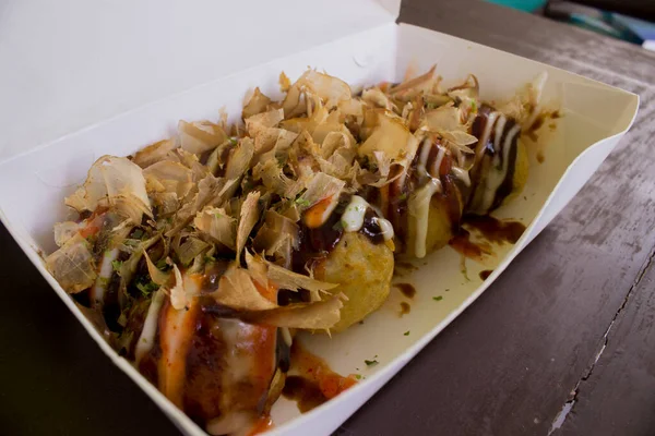 Takoyaki is food Japan, in the form of small balls made from dough flour filled with pieces of octopus. japanese food, isolated in wood background