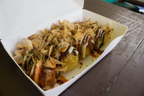 Takoyaki is food Japan, in the form of small balls made from dough flour filled with pieces of octopus. japanese food, isolated in wood background