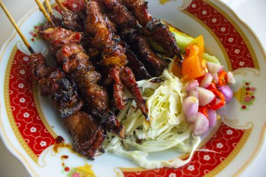 Sate kambing ya da sate klatak ya da kuzu satay ya da keçi eti satay dilimlenmiş lahana, kırmızı soğan, kırmızı biber, soya soslu domates ile servis edilir. izole edilmiş beyaz arkaplan 