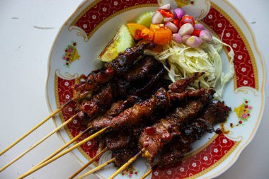 Sate kambing ya da sate klatak ya da kuzu satay ya da keçi eti satay dilimlenmiş lahana, kırmızı soğan, kırmızı biber, soya soslu domates ile servis edilir. izole edilmiş beyaz arkaplan 