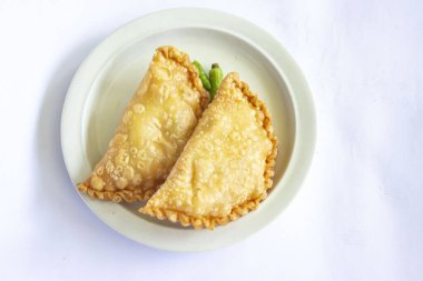 pastie cake or pastry cake or kue pastel served with green chili in little plate on wood background. indonesian pastel cake