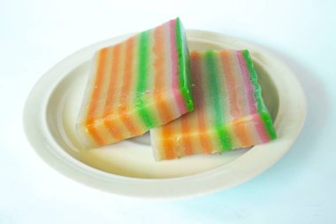 lapis cake or roti lapis or layer cake or lapis legit served in little plate isolated on white background made from rice flour, starch, coconut milk, sugar, salt and coloring
