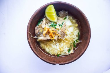 soto kwali. Beyaz arka planda izole edilmiş. Et lahanası, limon ve pirinçli Cava eti çorbası; geleneksel bir kwali kasesinde servis edilir (kilden yapılmış bir kap).)