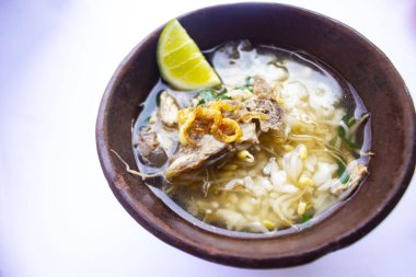 soto kwali. Beyaz arka planda izole edilmiş. Et lahanası, limon ve pirinçli Cava eti çorbası; geleneksel bir kwali kasesinde servis edilir (kilden yapılmış bir kap).)