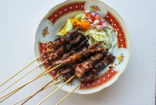 Sate kambing ya da sate klatak ya da kuzu satay ya da keçi eti satay dilimlenmiş lahana, kırmızı soğan, kırmızı biber, soya soslu domates ile servis edilir. izole edilmiş beyaz arkaplan 