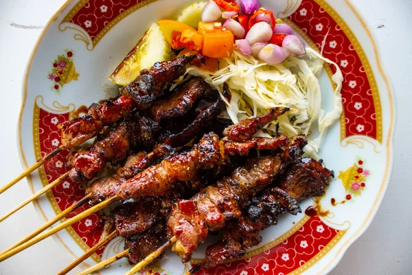 Sate kambing ya da sate klatak ya da kuzu satay ya da keçi eti satay dilimlenmiş lahana, kırmızı soğan, kırmızı biber, soya soslu domates ile servis edilir. izole edilmiş beyaz arkaplan 