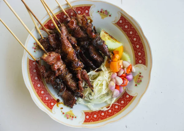 Sate kambing ya da sate klatak ya da kuzu satay ya da keçi eti satay dilimlenmiş lahana, kırmızı soğan, kırmızı biber, soya soslu domates ile servis edilir. izole edilmiş beyaz arkaplan 
