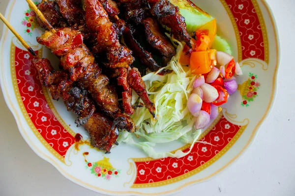 Sate kambing ya da sate klatak ya da kuzu satay ya da keçi eti satay dilimlenmiş lahana, kırmızı soğan, kırmızı biber, soya soslu domates ile servis edilir. izole edilmiş beyaz arkaplan 