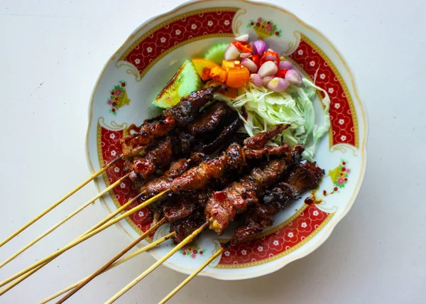 Sate kambing ya da sate klatak ya da kuzu satay ya da keçi eti satay dilimlenmiş lahana, kırmızı soğan, kırmızı biber, soya soslu domates ile servis edilir. izole edilmiş beyaz arkaplan 