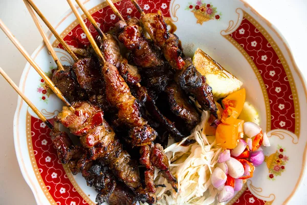 Sate kambing ya da sate klatak ya da kuzu satay ya da keçi eti satay dilimlenmiş lahana, kırmızı soğan, kırmızı biber, soya soslu domates ile servis edilir. izole edilmiş beyaz arkaplan 