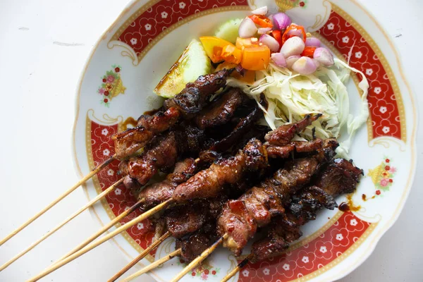 Sate kambing ya da sate klatak ya da kuzu satay ya da keçi eti satay dilimlenmiş lahana, kırmızı soğan, kırmızı biber, soya soslu domates ile servis edilir. izole edilmiş beyaz arkaplan 