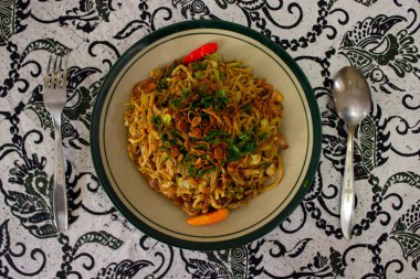 Mie Goreng Jawa ya da bakmi jawa ya da çatal kaşıklı Java noodle. Endonezya geleneksel sokak eriştesi Orta Java ya da Yogyakarta, Endonezya ahşap arka planda.