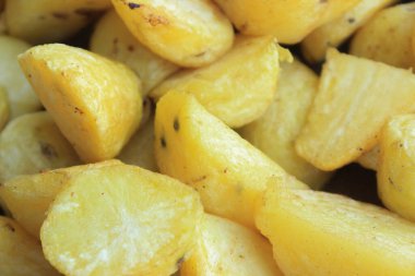 Fresh organic potato stand out among many large background potatoes in the field . Heap of potato root. Close-up potatoes texture.