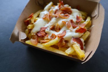 fried fries with with melted cheddar cheese or fried cheese with topping sausage slices on box