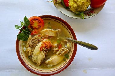 Sebzeli tavuk çorbası, domates, kase içinde kereviz, kaşık ve çatal. Siyah arkaplan