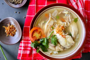  Sebzeli tavuk çorbası, domates, kase içinde kereviz, kaşık ve çatal. Siyah arkaplan