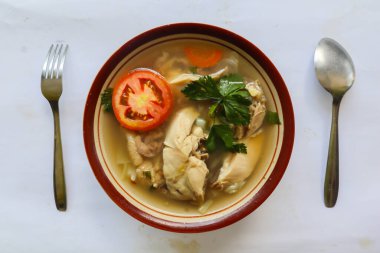 Sebzeli tavuk çorbası, domates, kase içinde kereviz, kaşık ve çatal. Siyah arkaplan