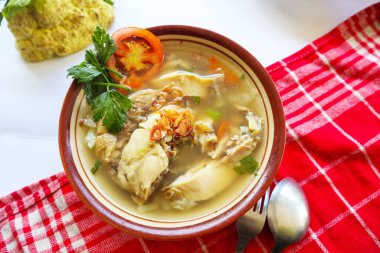 Sebzeli tavuk çorbası, domates, kase içinde kereviz, kaşık ve çatal. Siyah arkaplan