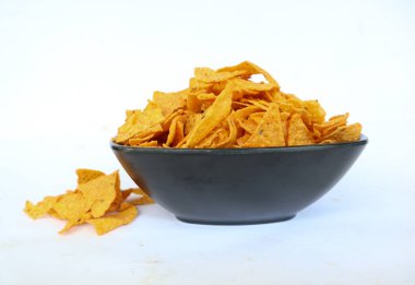 Tortilla cipsi, mısır cipsidir veya mısır cipsi olarak adlandırılır, kasede servis edilir, mısırdan yapılan siyah arka planda.