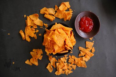 Tortilla cipsi, mısır cipsidir veya mısır cipsi olarak adlandırılır, kasede servis edilir, mısırdan yapılan siyah arka planda.