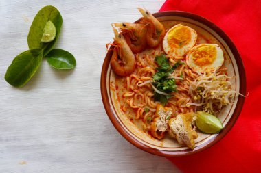 laksa, laksa curry made from vermicelli, noodles, bean sprouts, egg, tofu lime, and shrimp with a spicy soup sauce that is rich in spices. laksa served on bowl, isolated on white background.