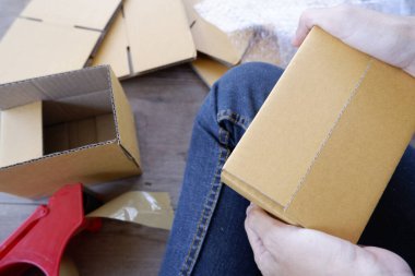 Katlanan kahverengi paket kutusunda oturan kişi