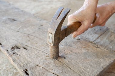 Dişi eller eski tahta kalaslara çivi çakıyor.