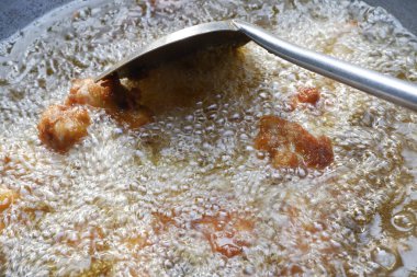 Büyük bir tavada yağda kızarmış tavuk.