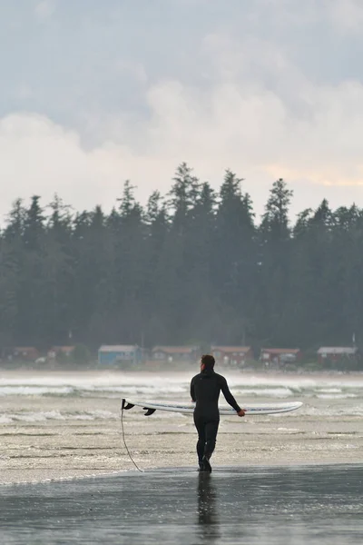 Bir sörfçü Kanada 'daki Tofino British Columbia' da sahil boyunca sörf tahtasını taşır. — Stok fotoğraf