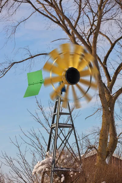 Um pequeno moinho de vento ou turbina eólica em um ambiente rural com lâminas giratórias — Fotografia de Stock