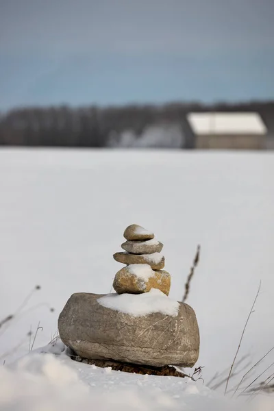 Kışın tarlada bir Inukshuk ve arka planda bir ahır.