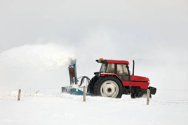 Trattore rosso neve soffiando un vialetto in un ambiente rurale — Foto Stock