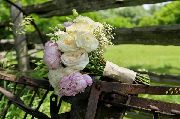 Close up of White Rose and Pink Peonies Wedding Bouquet on Rusty Farm Equipment