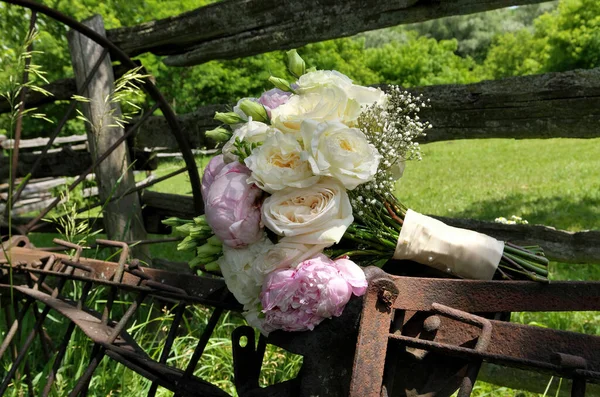Close up of White Rose and Pink Peonies Wedding Bouquet on Rusty Farm Equipment