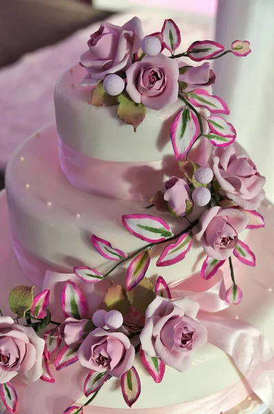 Elegante weiße Hochzeitstorte umhüllt von exquisiten Fondant- und Marzipan-Rosen und rosa Schleife — Stockfoto