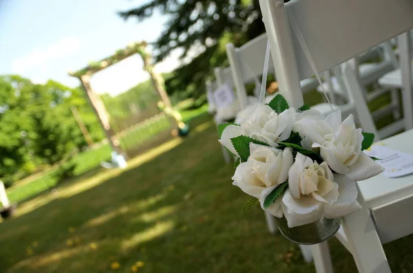 Белые стулья, украшенные букетами из белой розы, ждут гостей на свадьбе в саду — стоковое фото