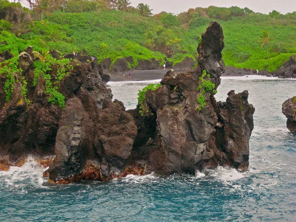Ziyaretçiler Hana, Hawaii 'deki Waianapanapa Eyalet Parkı' nda bulunan Maui adasındaki Lava Kayalıklarını keşfediyorlar.