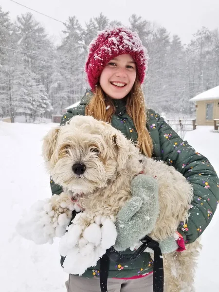 Gülümseyen genç bir kızın portresi Son derece tüylü köpeğini kaldırıyor Pençeleri karda pişmiş