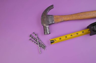 Çekiç, çivi ve mezuranın düzleşmesi Lavanta Mor bir arka planda izole edildi.