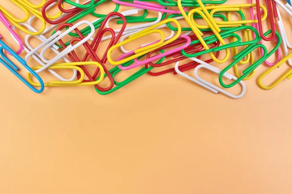 Multicolored Paperclips Isolated on a Cheerful Orange Beige Background with Copy Space on Bottom — Stock Photo, Image