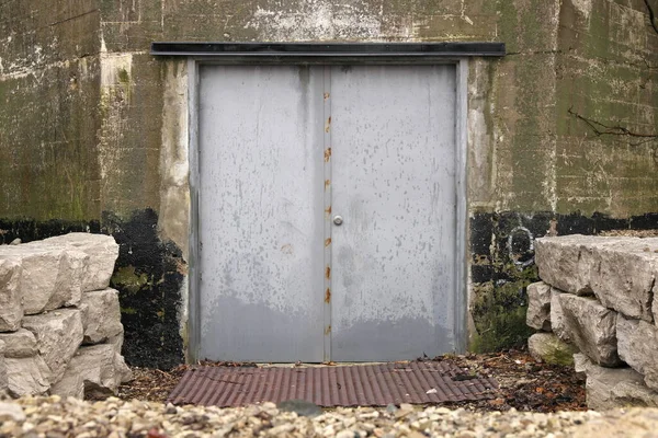 Gruselige graue Stahldoppeltür führt in feuchtes Betongebäude — Stockfoto