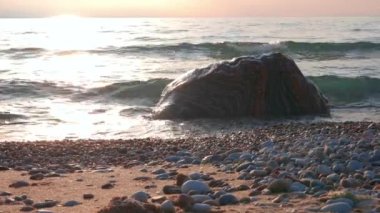 Gün batımında Sahilde Küçük Dalgaların Renkli Kayaların Üzerinde Kırılmasının Kaydırıcı Çekimi