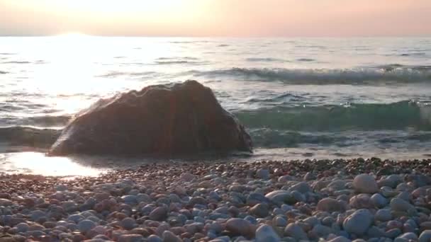 Slider Shot of Small Waves Breaking Over Colorful Boulder Along Beach at Sunset — Video