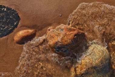 Renkli Kayalar ve Kayalar ile Noktalı Küçük Dalgalar Sahile Yuvarlanıyor