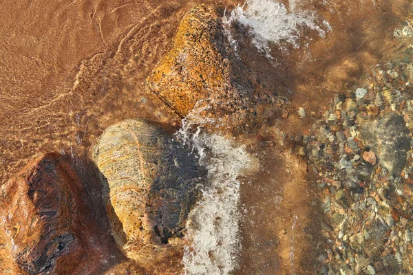 Directly Above Shot of Small Waves Rolling into Beach Dotted with Colorful Rocks and Boulders — стоковое фото