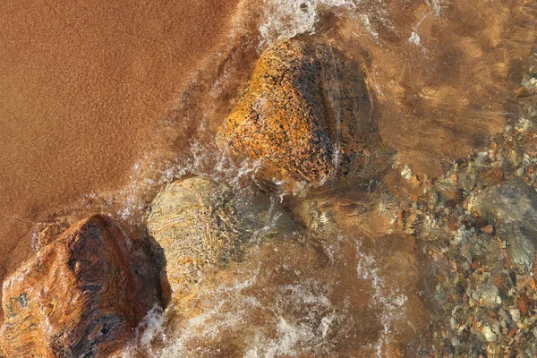 Прямо над выстрелом малых волн катится на пляж с красочными скалами и валунами — стоковое фото