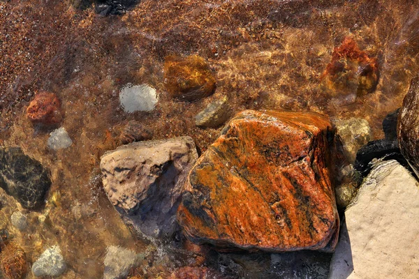 Directly Above Shot of Small Waves Rolling into Beach Dotted with Colorful Rocks and Boulders — стоковое фото