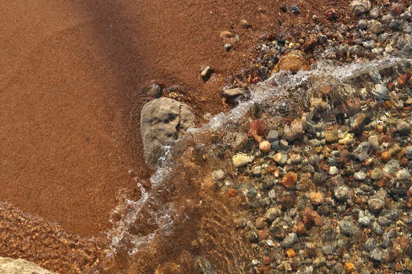 Small Waves Rolling into Sandy Beach Dotted with Colorful Pebbles, Rocks, and Stones — стоковое фото