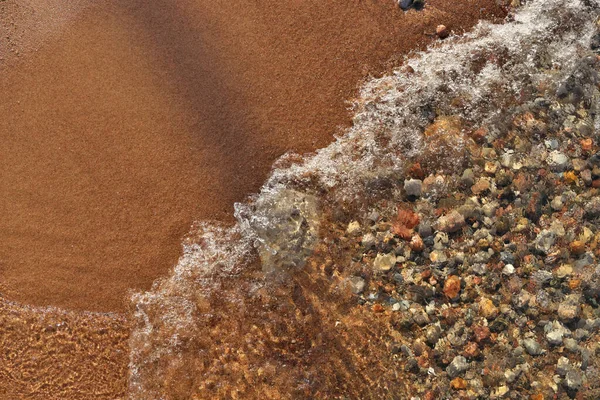 Маленькие водопады, скатывающиеся в песчаный пляж, усеянный разноцветными булыжниками, розами и камнями — стоковое фото